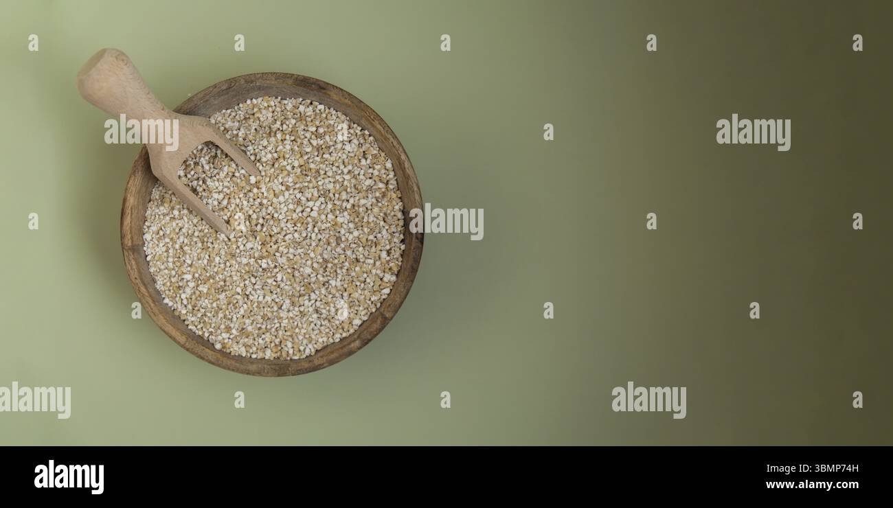 Orzo macinato fine in uno spazio di copia su sfondo verde. Specie di grani di farro intero. Ingrediente alimentare vegano ricco di fibre ad alto contenuto proteico. Senza glutine Foto Stock