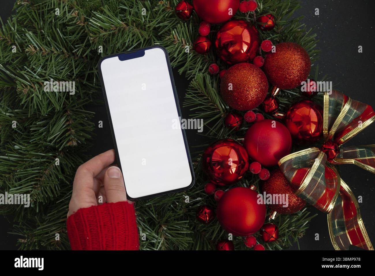 Modello per smartphone con schermo bianco sulla corona di Natale fatta a mano. Natale ecocompatibile senza sprechi. Decorazione sostenibile dei biglietti d'auguri Foto Stock