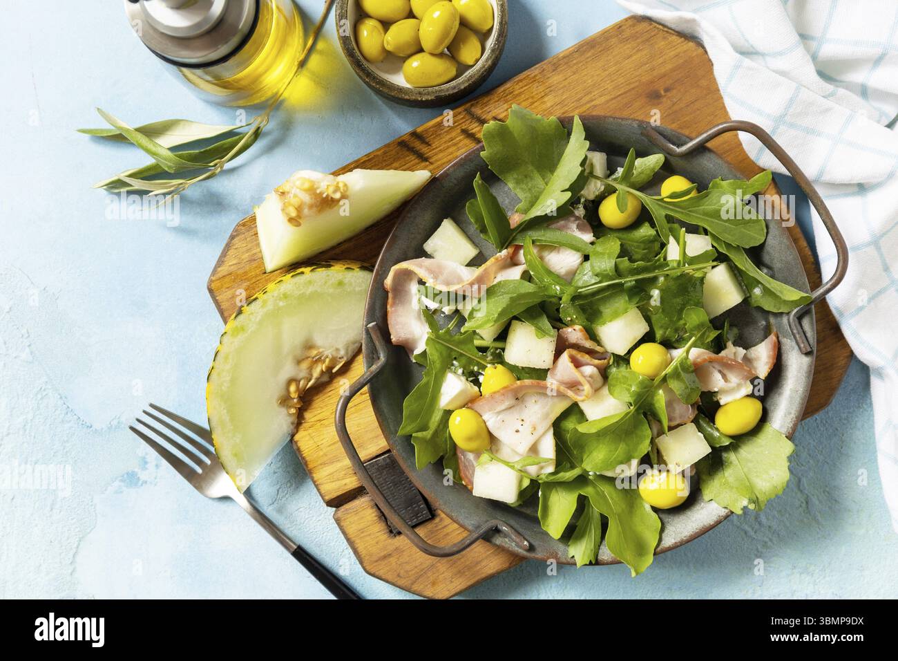 Insalata mediterranea estiva con melone, pancetta, olive, formaggio bianco e rucola su fondo di pietra blu. Antipasto tradizionale spagnolo e italiano. Vi Foto Stock