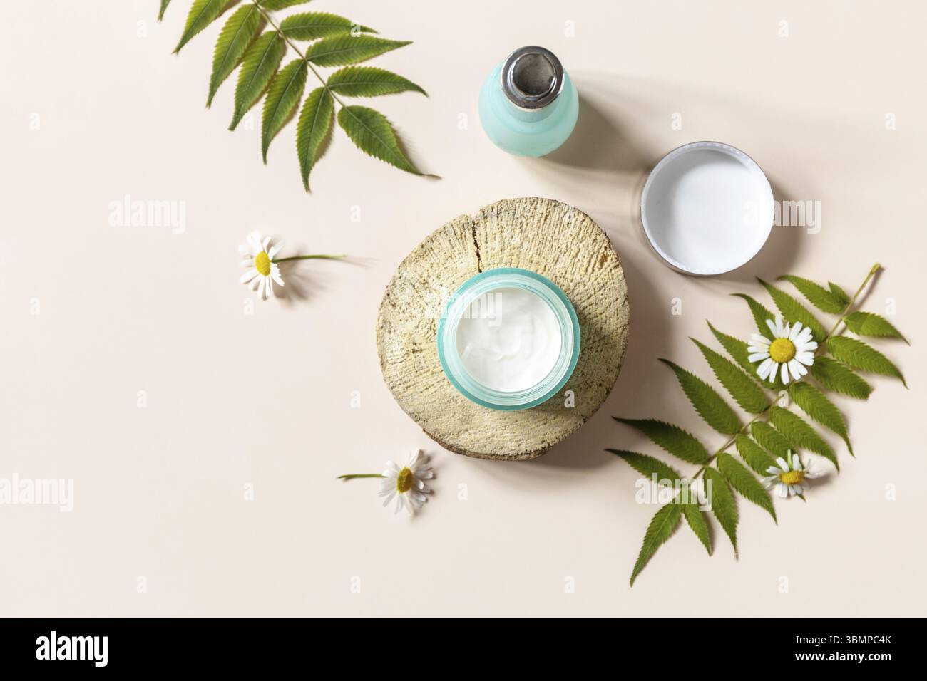 Igiene quotidiana e cura della pelle femminile sana. Crema cosmetica e siero del viso con galleggianti cammimili su sfondo blu. SPA naturale biologico bellezza Produ Foto Stock