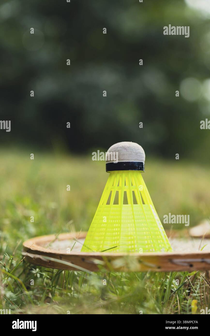 Il racket di badminton e il rubinetto giacciono sull'erba verde. Attività ricreative all'aperto e aria fresca. Stile di vita sano natura connessione sport attività estive. St Foto Stock
