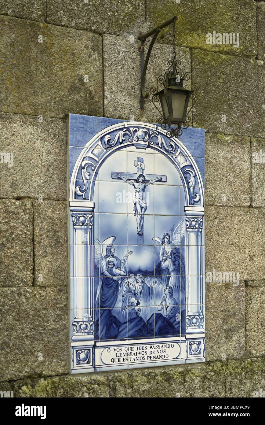 Azulejo raffigura la crocifissione di Gesù Cristo con angeli e un'antica lampada appesa su una parete di granito Foto Stock