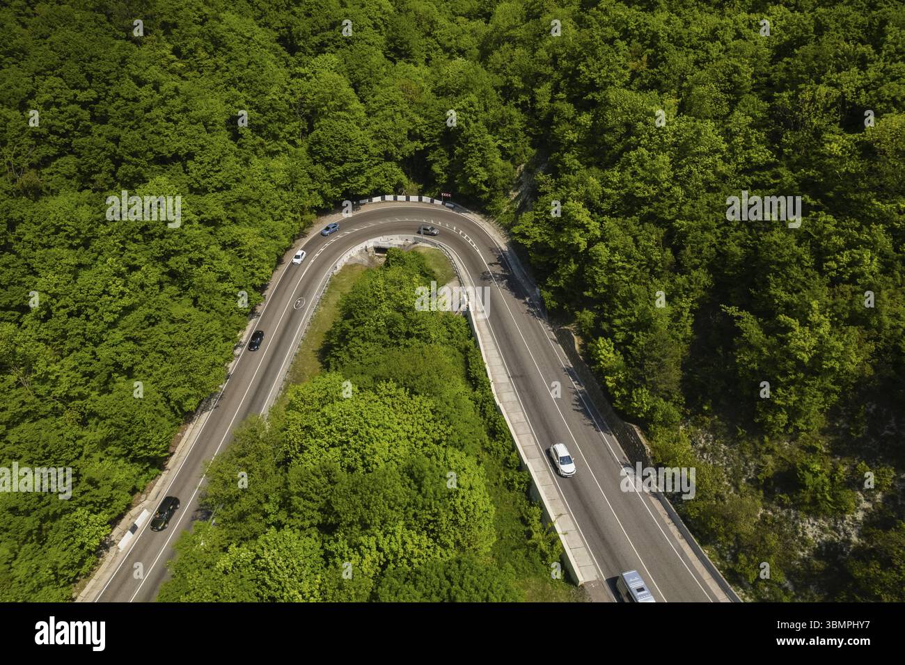 Vista aerea della strada tortuosa dall'alto passo di montagna. Ottimo viaggio in auto attraverso i fitti boschi. Vista a volo d'uccello Foto Stock