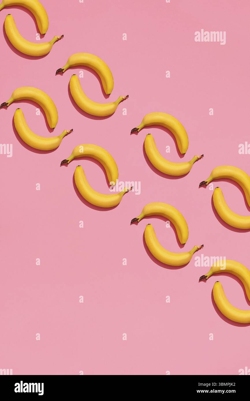 Progettazione di alimenti. Composizione del modello di un paio di banane che giacciono accanto ad uno sfondo rosa. Modello, vista dall'alto, stile piatto Foto Stock