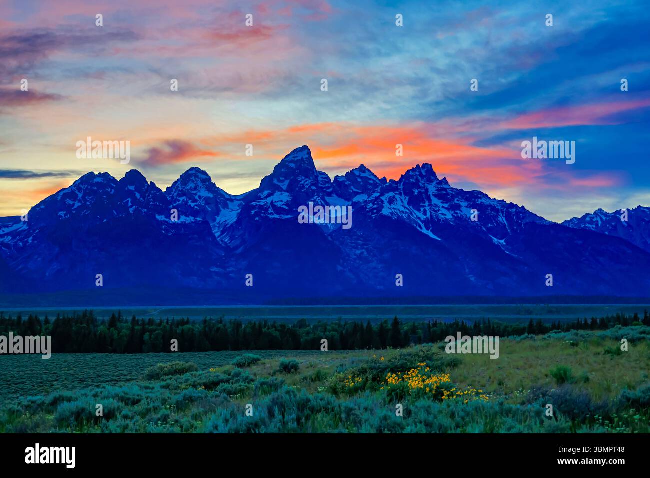 Il tramonto illumina il cielo sopra la catena montuosa Teton, con la Grand Teton Mountain al centro della cornice. Foto Stock