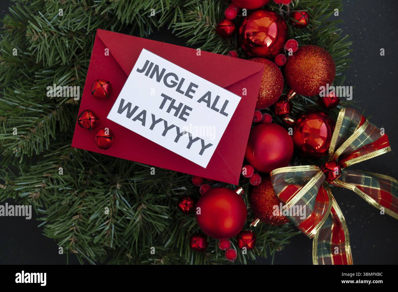 Corona di Natale fatta a mano con decorazioni natalizie con busta rossa e nota di carta con JINGLE TUTTO IL testo. Festeggiamenti per le vacanze invernali Foto Stock