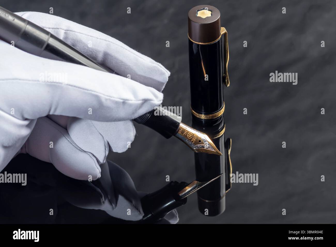 Stilografica nera su sfondo grigio marmo. Indossa un guanto bianco. Cancelleria Foto Stock