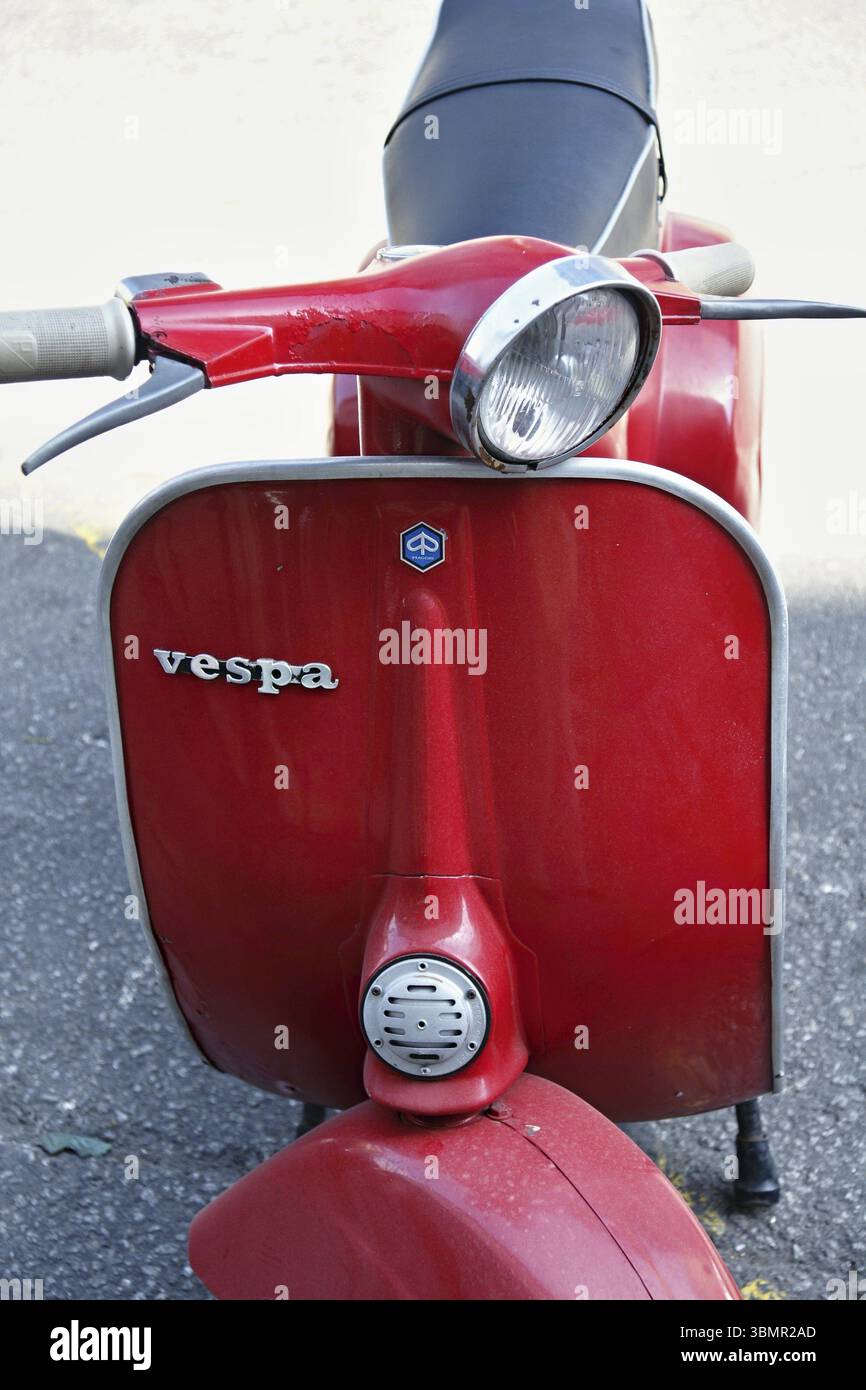Vespa rossa classica parcheggiata su una strada cittadina, che mostra il suo design iconico e il fascino vintage Foto Stock