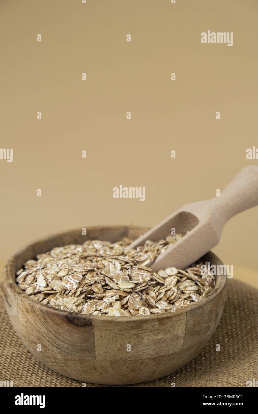 Porridge di farina d'avena grezza in uno spazio di copia beige neutro. Specie di grani di farro intero. Ingrediente alimentare vegano ricco di fibre ad alto contenuto proteico. Glu Foto Stock