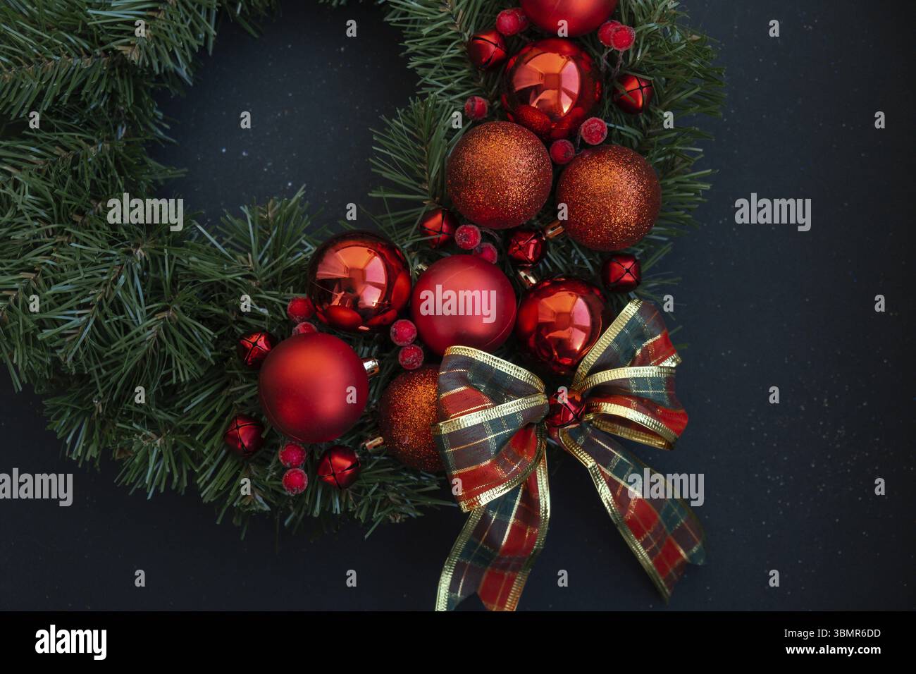 Corona di Natale realizzata a mano con decorazioni rosse natalizie. Preparazione per le festività natalizie, maestria nella creazione creativa dell'arredamento. Attività pratiche Foto Stock