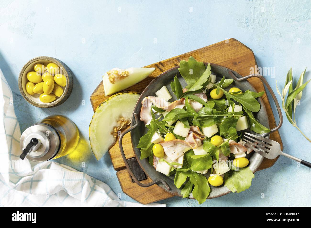 Insalata mediterranea estiva con melone, pancetta, olive, formaggio bianco e rucola su fondo di pietra blu. Antipasto tradizionale spagnolo e italiano. Vi Foto Stock