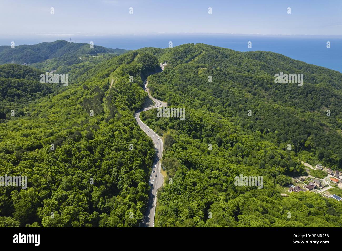 Vista aerea della strada tortuosa dall'alto passo di montagna. Ottimo viaggio in auto attraverso i fitti boschi. Vista a volo d'uccello Foto Stock