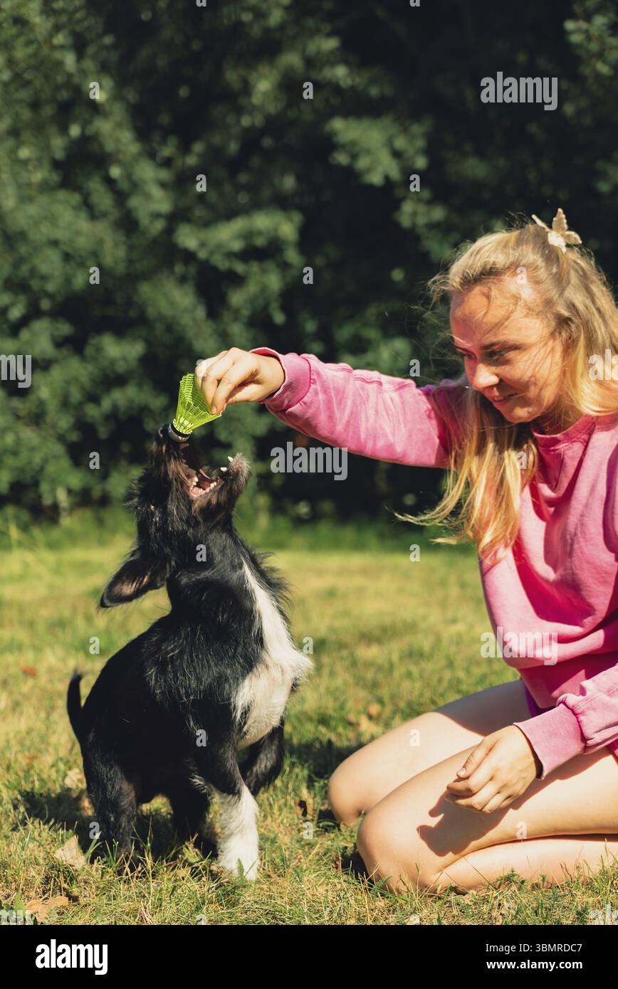 Donna che trascorre del tempo con il suo animale domestico giocando a Badminton Shuttlecock su erba verde. Attività ricreative all'aperto e aria fresca d'estate. Stile di vita sano Foto Stock