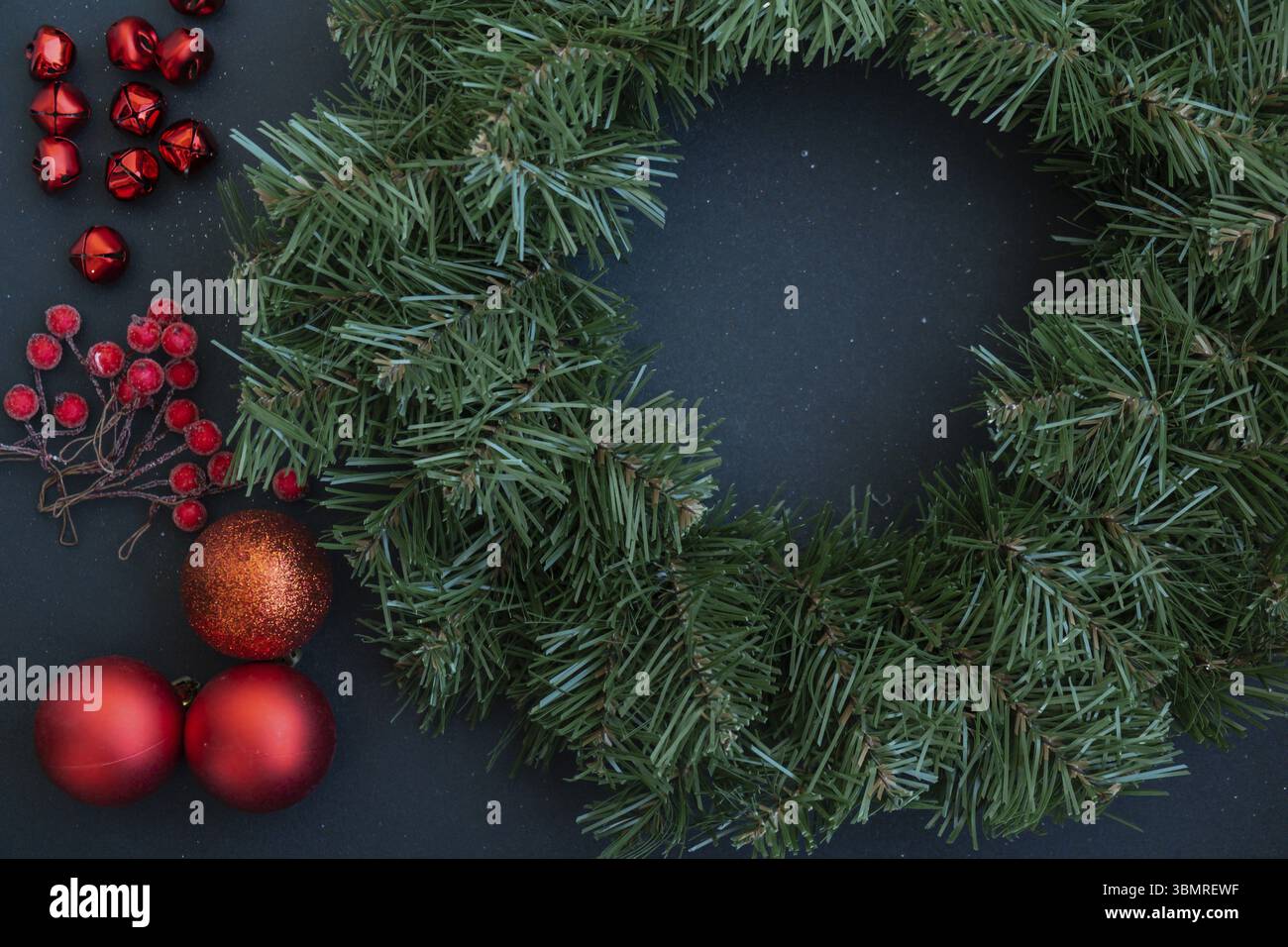 Corona di Natale realizzata a mano con decorazioni rosse natalizie. Preparazione per le festività natalizie, maestria nella creazione creativa dell'arredamento. Attività pratiche Foto Stock