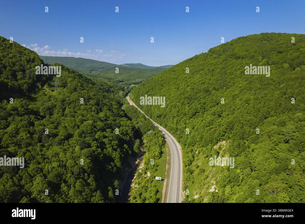 Vista aerea della strada tortuosa dall'alto passo di montagna. Ottimo viaggio in auto attraverso i fitti boschi. Vista a volo d'uccello Foto Stock
