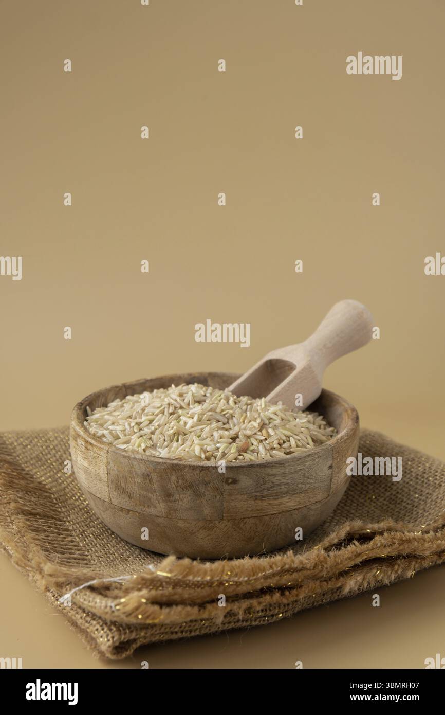 Riso marrone in uno spazio di copia beige neutro. Specie di grani di farro intero. Ingrediente alimentare vegano ricco di fibre ad alto contenuto proteico. Senza glutine Foto Stock