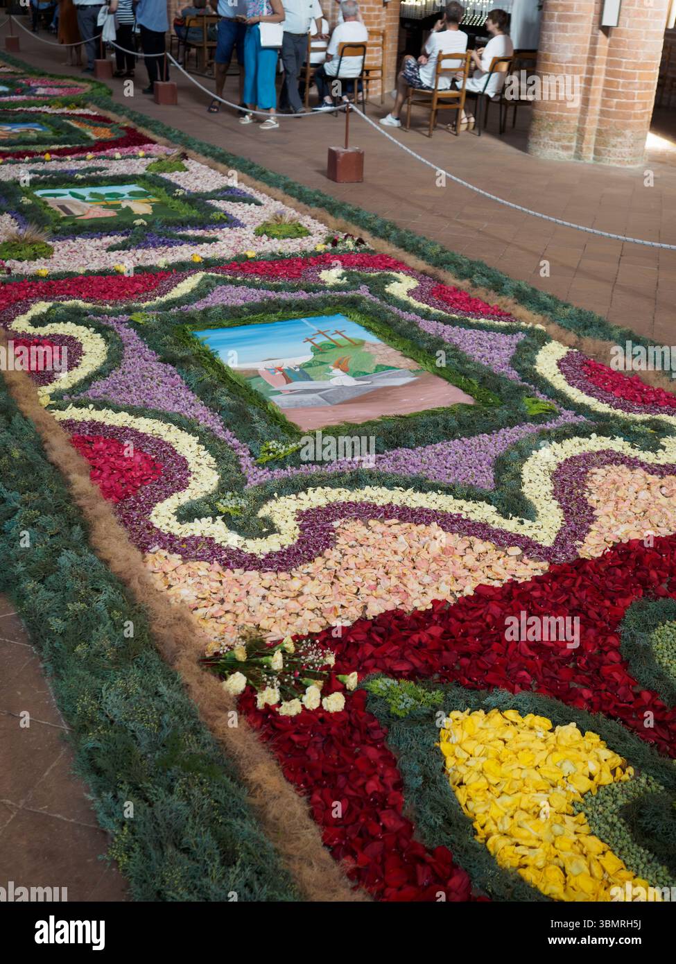 Alseno, Italia 22 giugno 2025 petali di fiori colorati che creano intricati motivi e rappresentazioni religiose sul pavimento di Chiaravalle della Colomba ABB Foto Stock