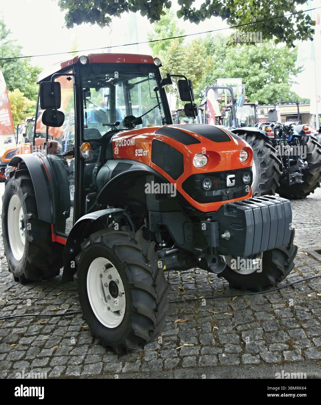 Il moderno trattore Goldoni 90 GT arancione parcheggiato su una strada acciottolata, mostra il suo potente motore e le sue caratteristiche avanzate Foto Stock