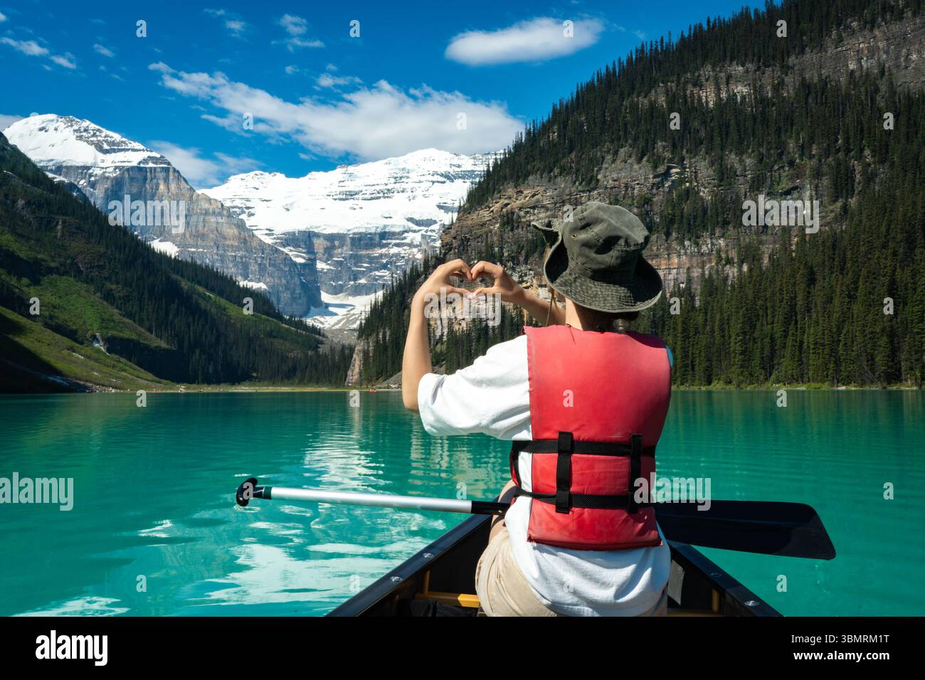 Persona che forma il cuore con le mani mentre canoa sul lago alpino. Foto Stock