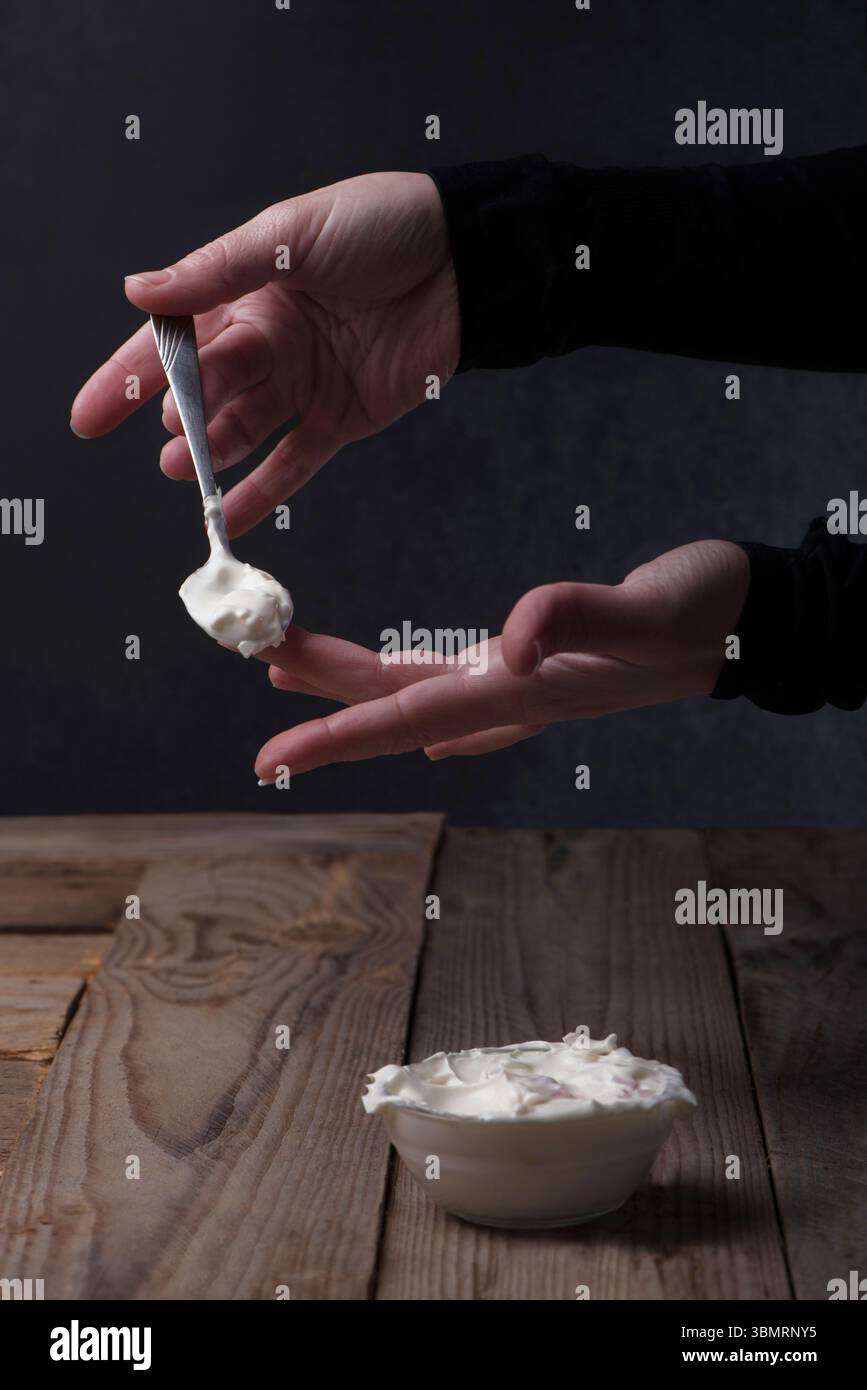 Immagine artistica che mostra mani eleganti servendo con grazia la maionese, enfatizzando texture, movimento e presentazione culinaria. Foto Stock