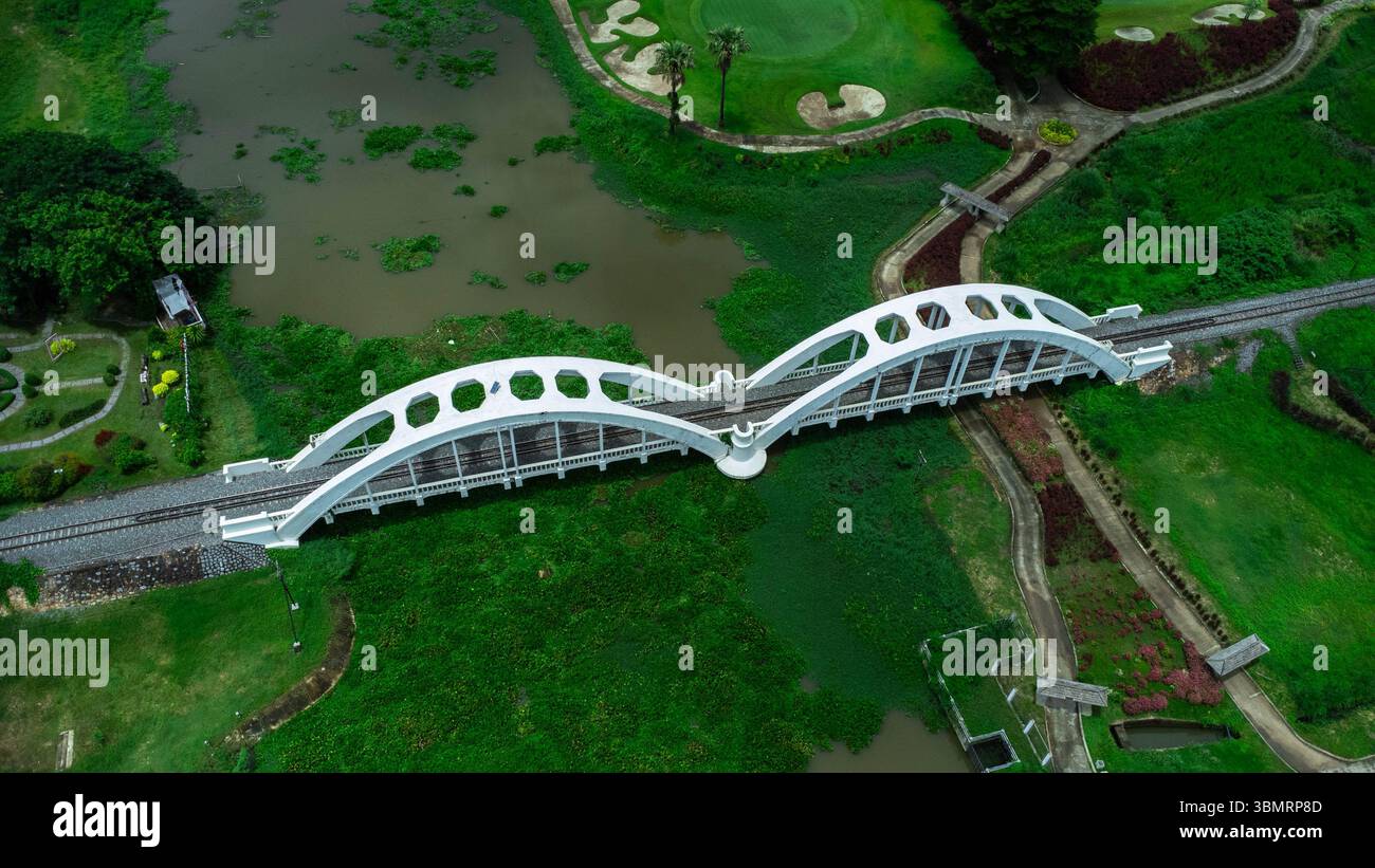 Veduta aerea del Ponte Bianco di Tha Chomphu, Lamphun, Thailandia con fiume, alberi di foresta e verde collina di montagna. Un vecchio ponte ferroviario sul fiume. T Foto Stock
