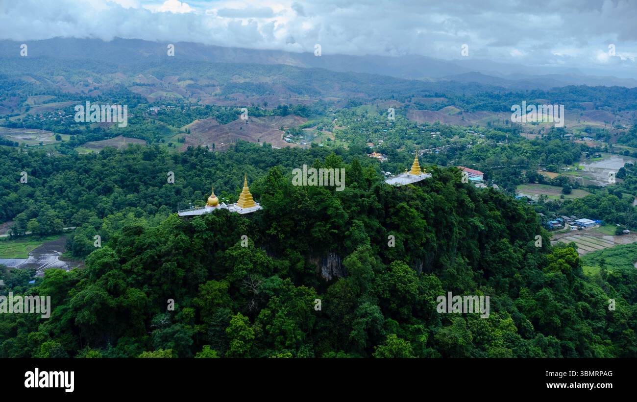 Il paesaggio della stagione delle piogge del villaggio di montagna al mattino e le montagne sullo sfondo, la statua del Buddha, il tempio e le montagne sono visibili come punto panoramico Foto Stock