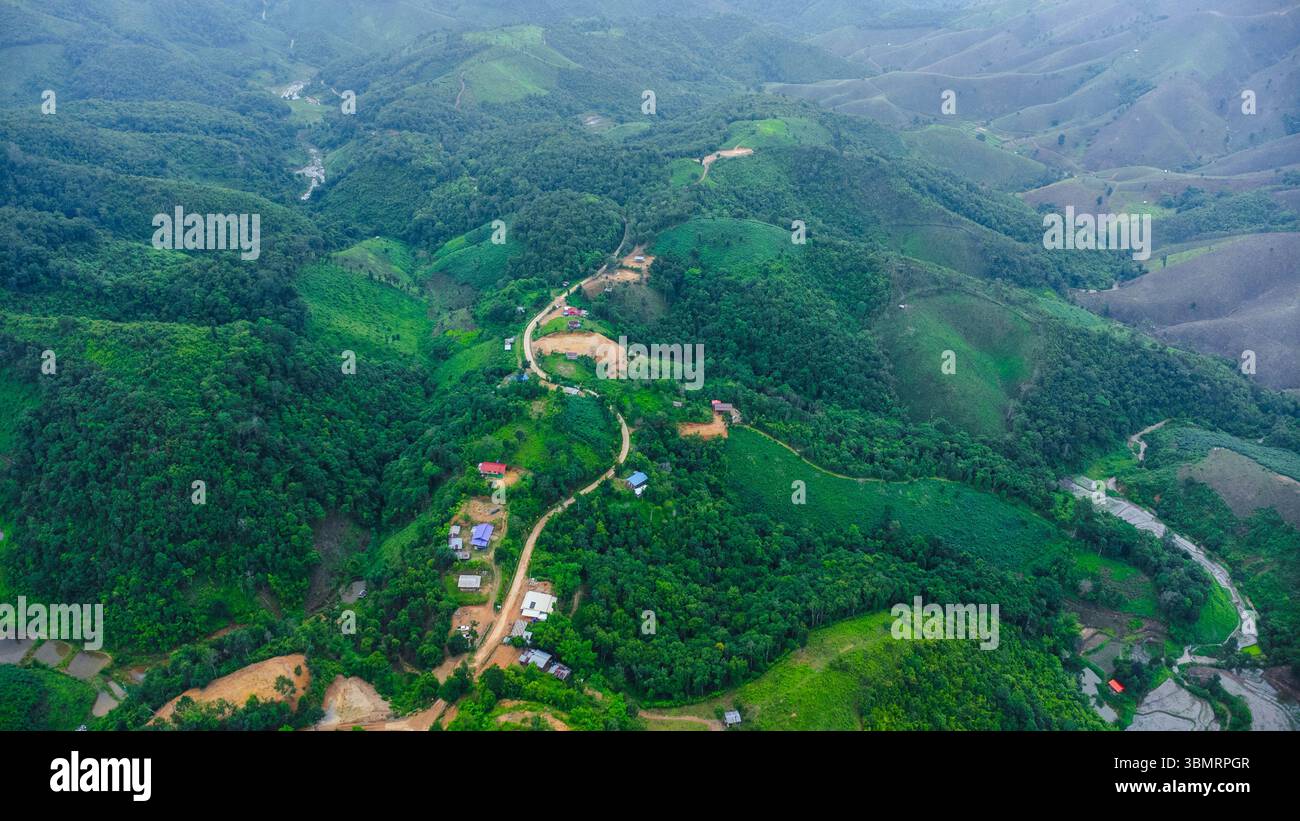 Paesaggio di stagione delle piogge di un villaggio di montagna al mattino e montagne sullo sfondo. Foto Stock