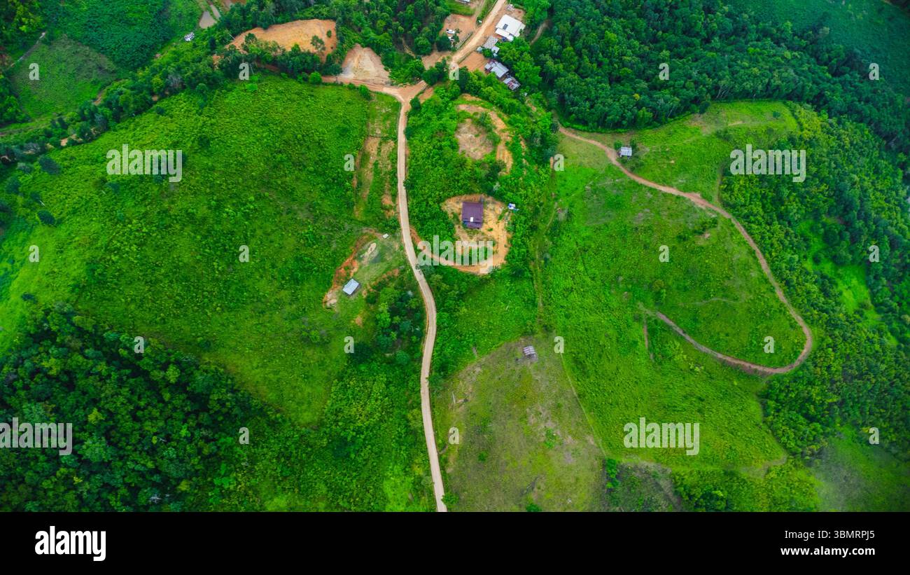 Paesaggio di stagione delle piogge di un villaggio di montagna al mattino e montagne sullo sfondo. Foto Stock