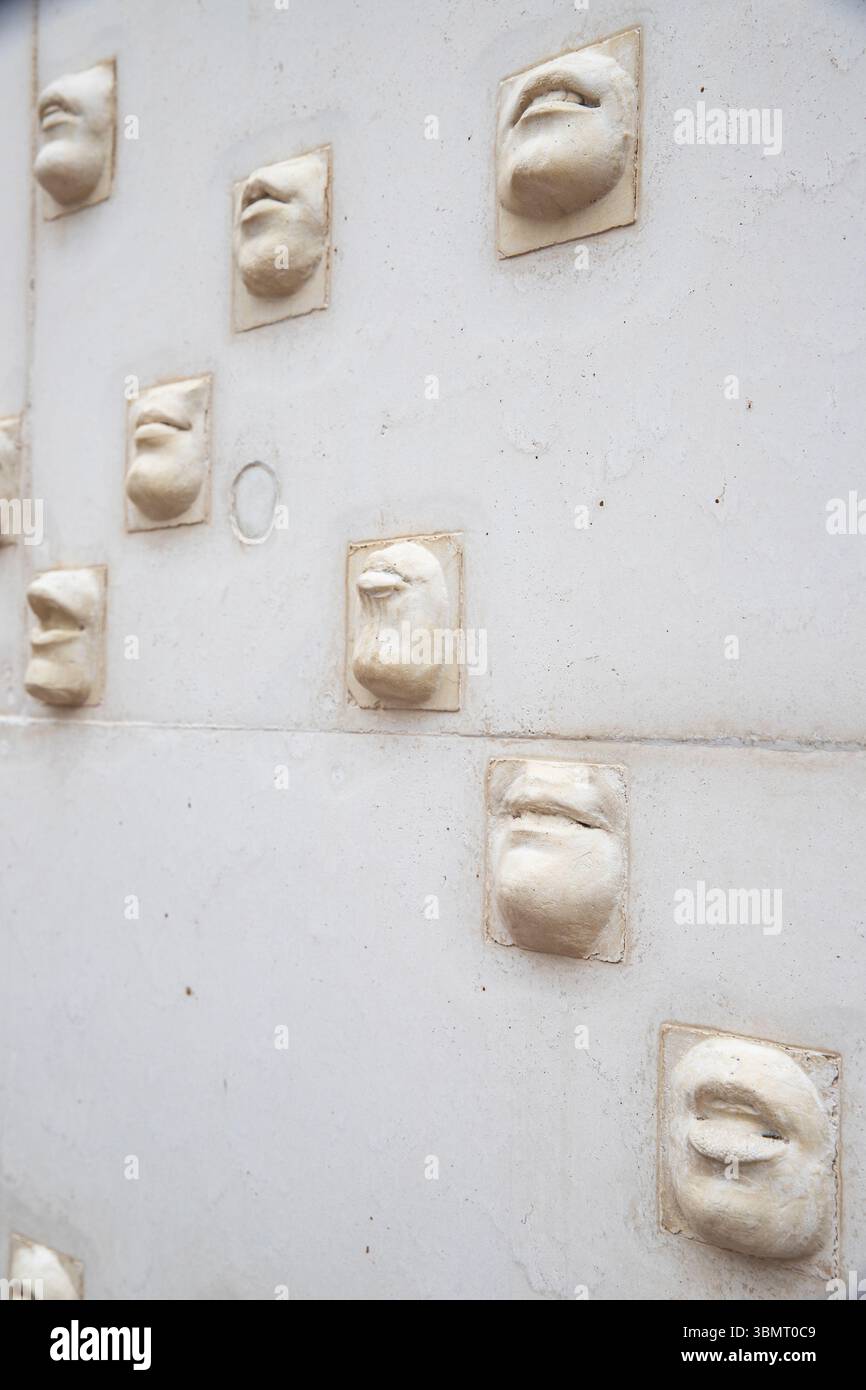 Volti scolpiti su un muro bianco come oggetto d'arte a Minorca, Spagna 08.03.2025 Foto Stock