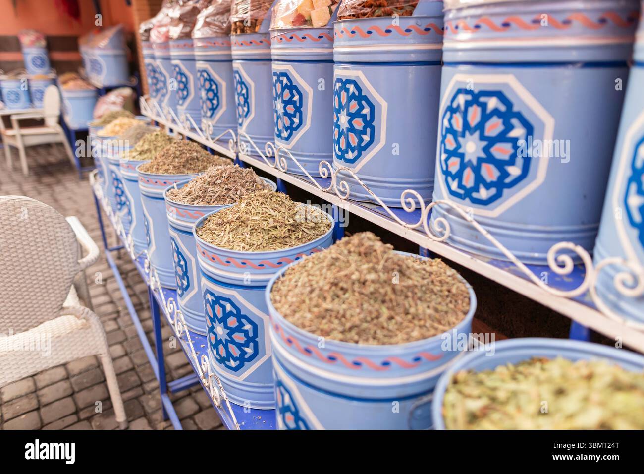 Vista ravvicinata delle erbe essiccate assortite nel mercato marocchino delle spezie - contenitori dipinti blu con motivi tradizionali Foto Stock