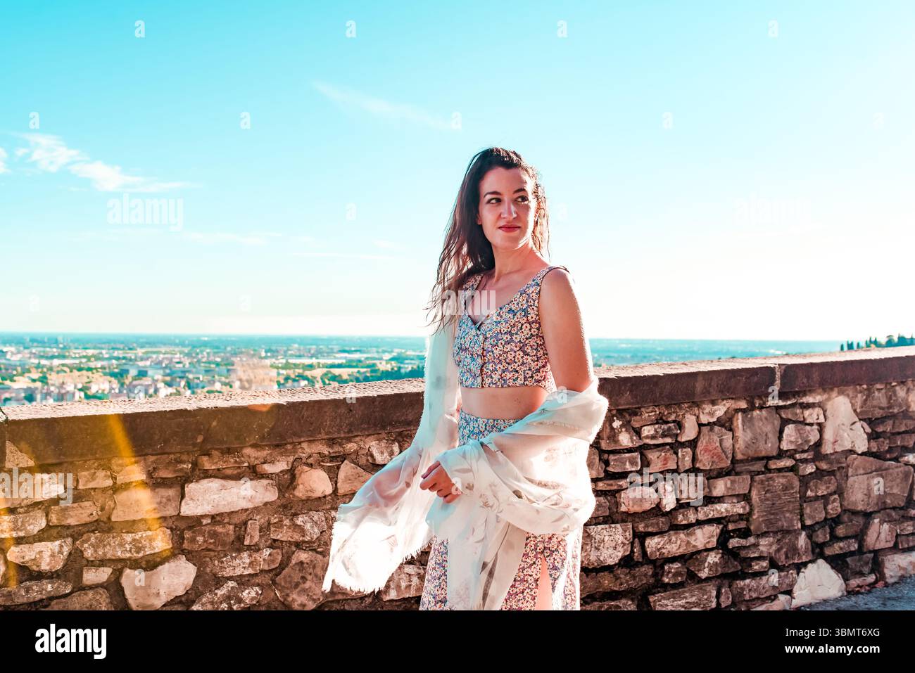 Donna sicura di sé che gode della vista estiva da una terrazza panoramica con un abito floreale Foto Stock