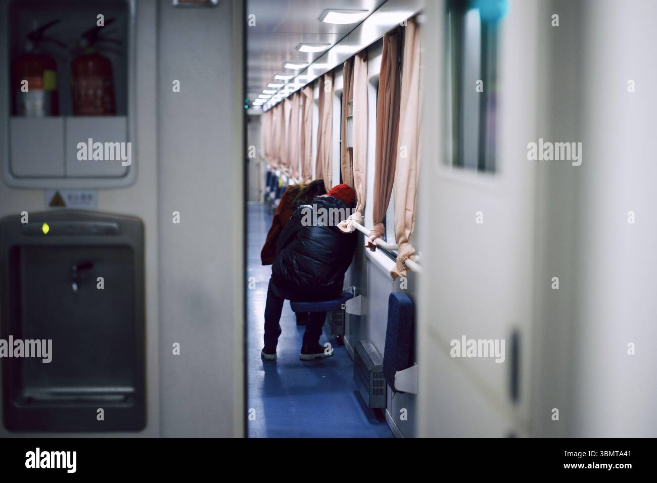 Il passeggero del corridoio ferroviario notturno cinese si appoggia al finestrino Foto Stock