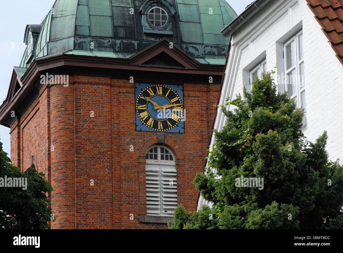 La torre in mattoni della chiesa di St. Jürgen a Kappeln, Germania, con il suo caratteristico orologio e la cupola verde in rame Foto Stock