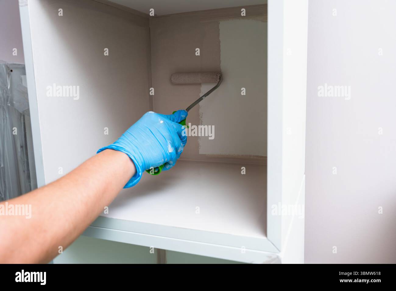 Pittore in boschetti che dipinge o ricopre mobili in diversi colori con rullo per pittura, trasformazione di mobili, progetto fai da te Foto Stock