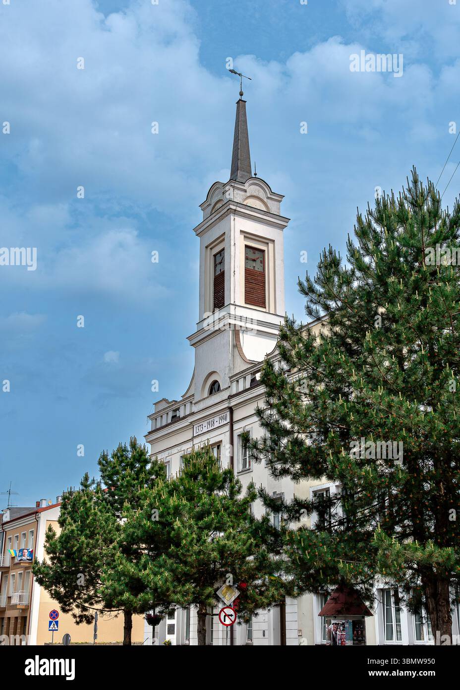 Municipio di Ostrołęka in Piazza Józef BEM. Un edificio neoclassico con una torre dell'orologio, circondato dal verde e dalla vita urbana nel centro della città. Foto Stock