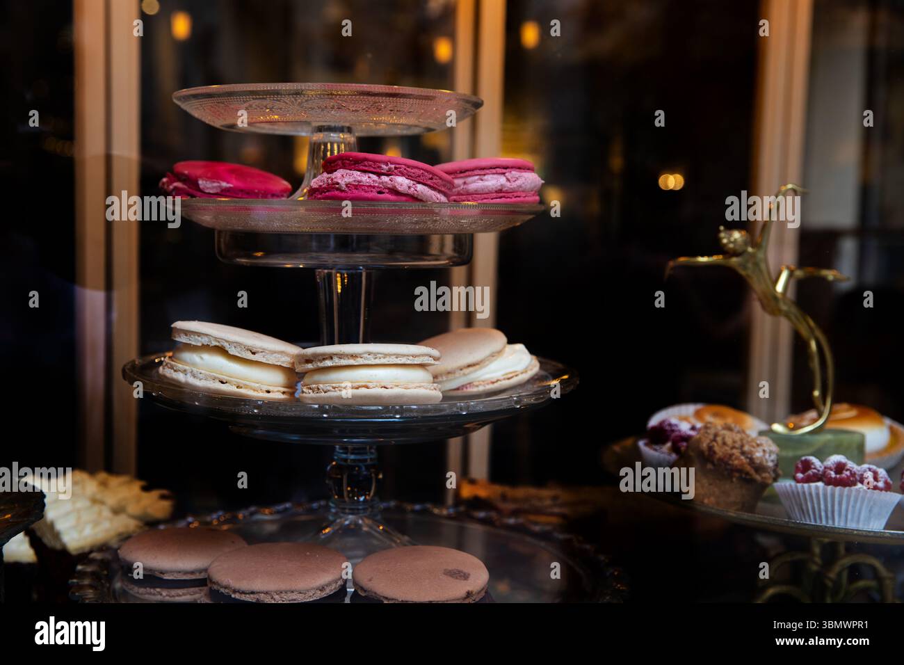 Macaron colorati su un banco di vetro in una pasticceria, deliziosi pasticcini e vari dessert Foto Stock