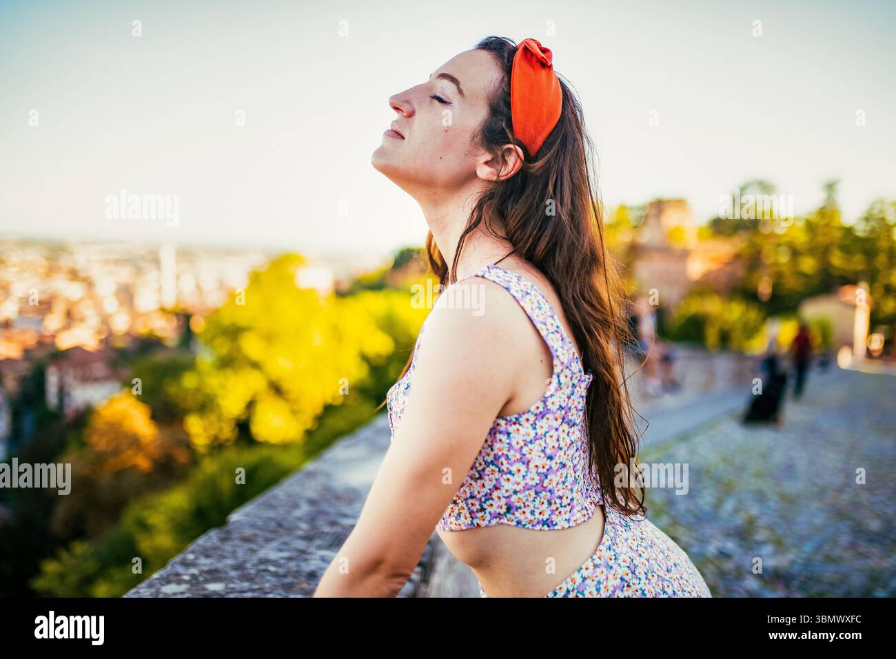 Giovane donna che si gode il tramonto con gli occhi chiusi e espressione pacifica Foto Stock
