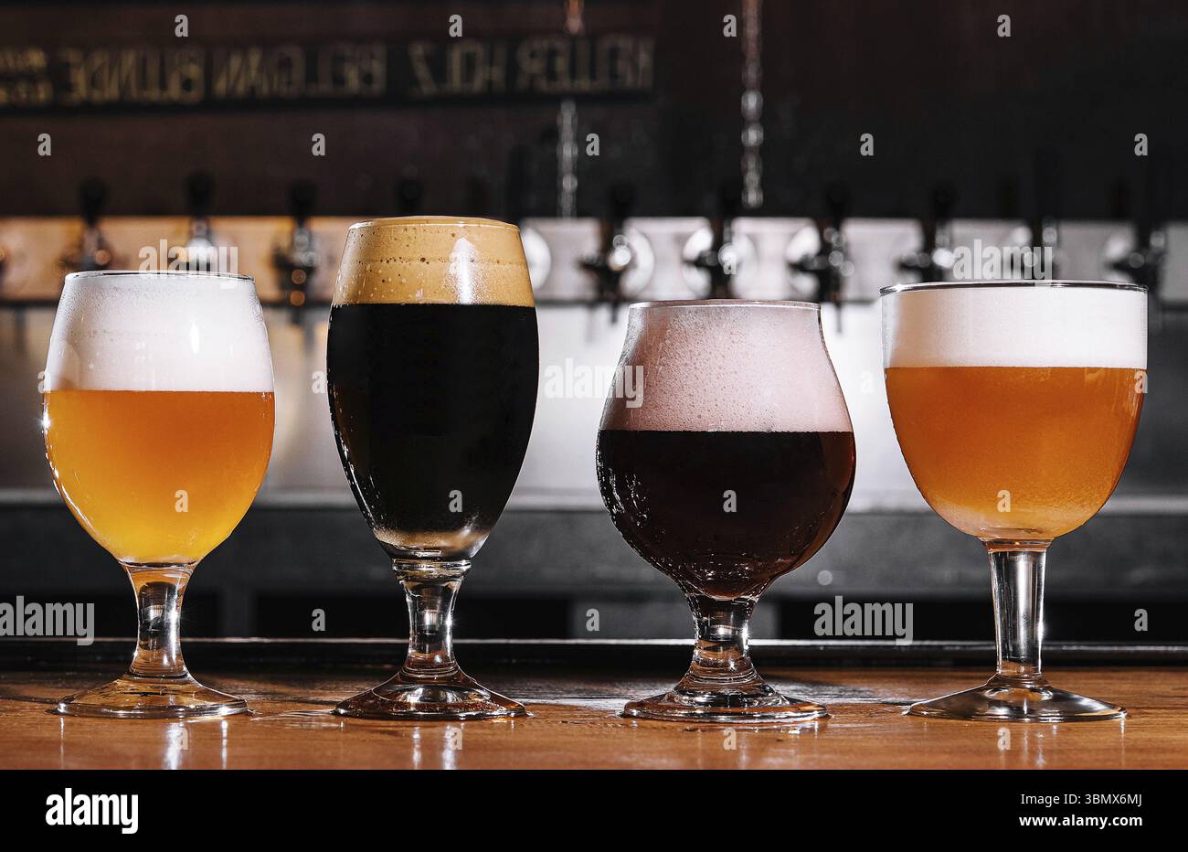 Natura morta del cibo, diversi tipi di birra artigianale in bicchieri sul tavolo all'interno del pub alla luce del giorno Foto Stock