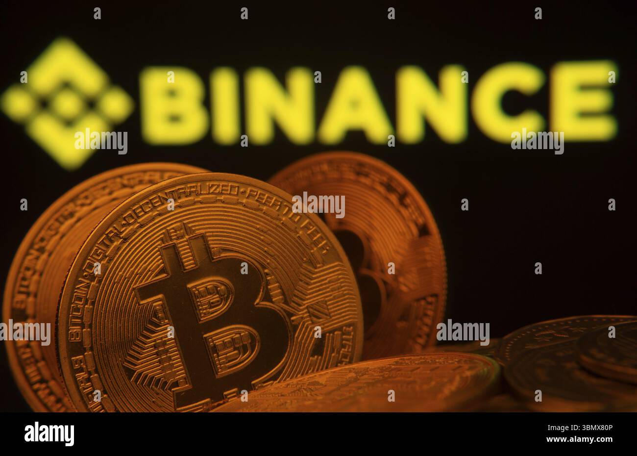 Dhaka, Bangladesh- 22 giugno 2025: Primo piano delle monete Bitcoin con il logo Binance visibile su uno schermo sullo sfondo Foto Stock