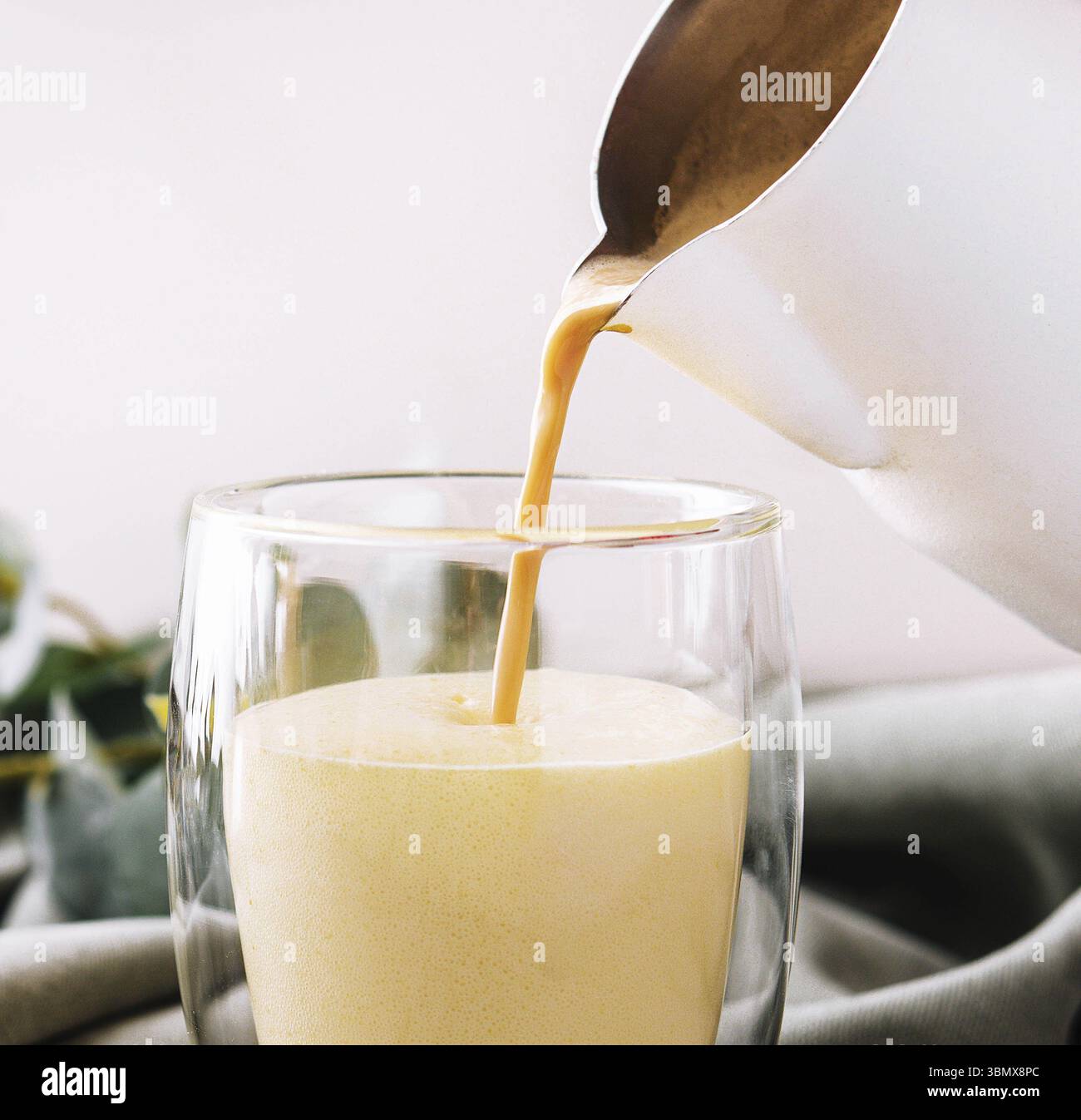 Natura morta degli alimenti, versando un caffè con latte dalla teiera alla tazza di vetro Foto Stock