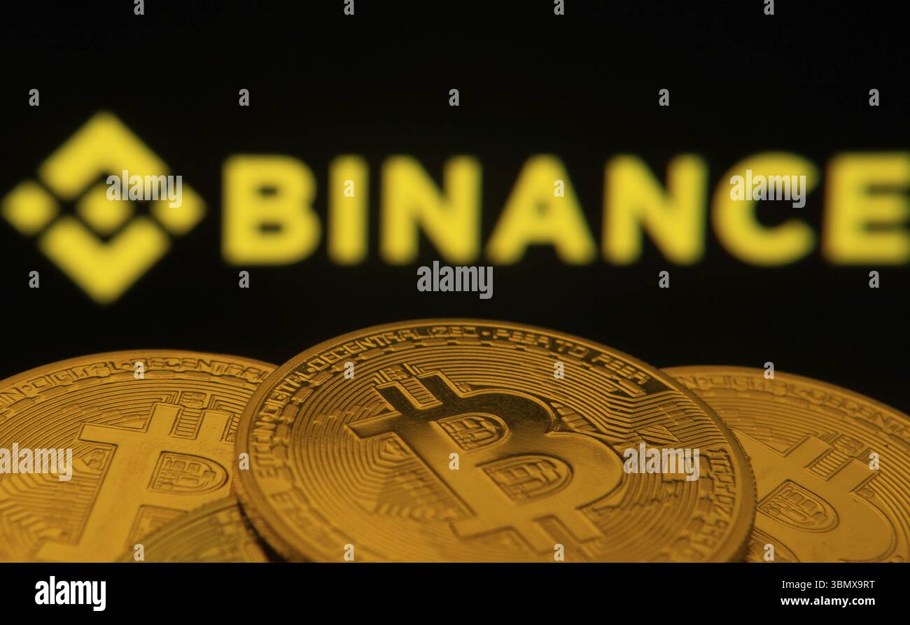 Dhaka, Bangladesh- 22 giugno 2025: Primo piano delle monete Bitcoin con il logo Binance visibile su uno schermo sullo sfondo Foto Stock