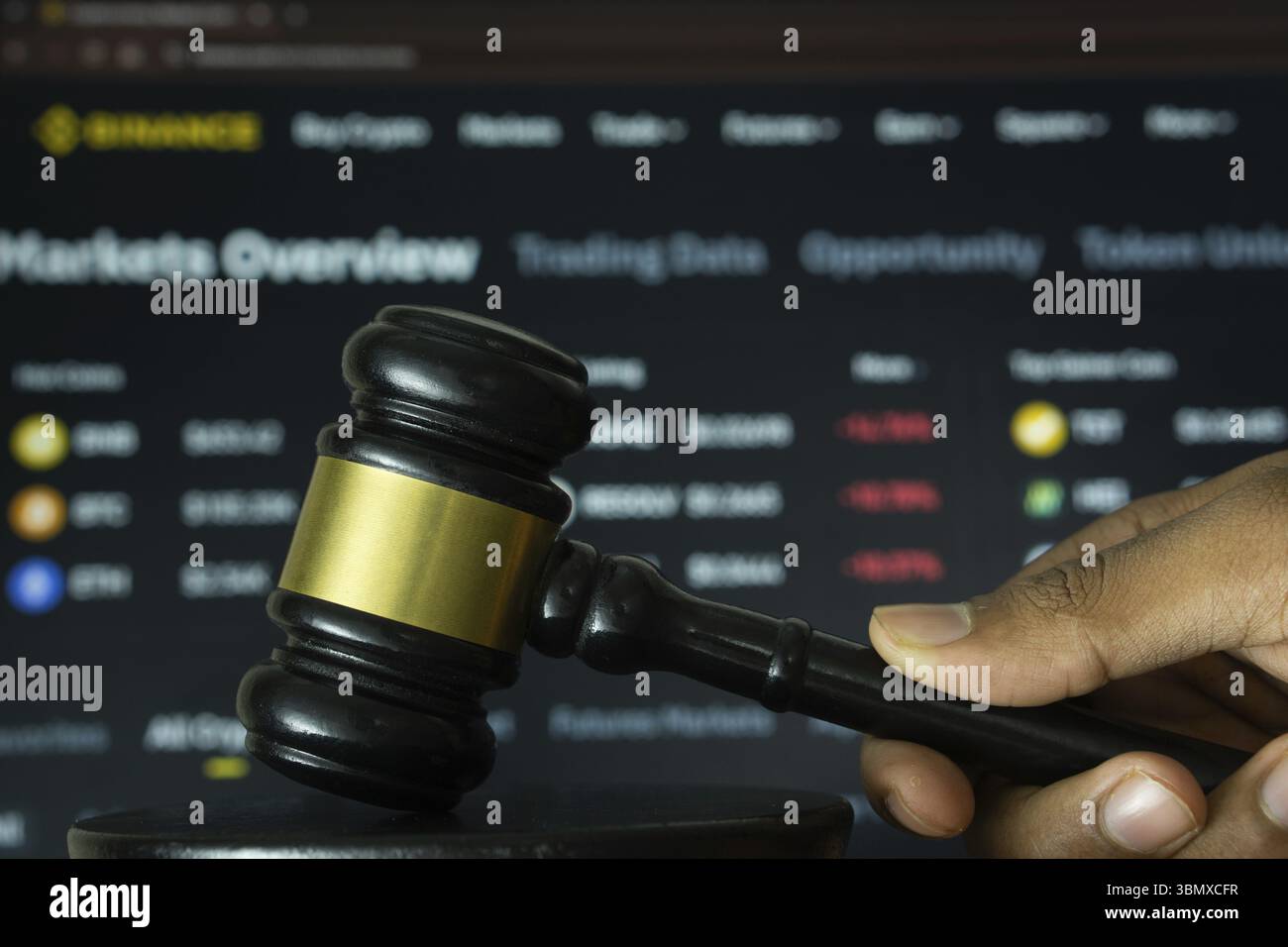 Dhaka, Bangladesh - 20 giugno 2025: Una mano tiene un martelletto davanti a uno schermo del computer che visualizza il sito web di binance Foto Stock