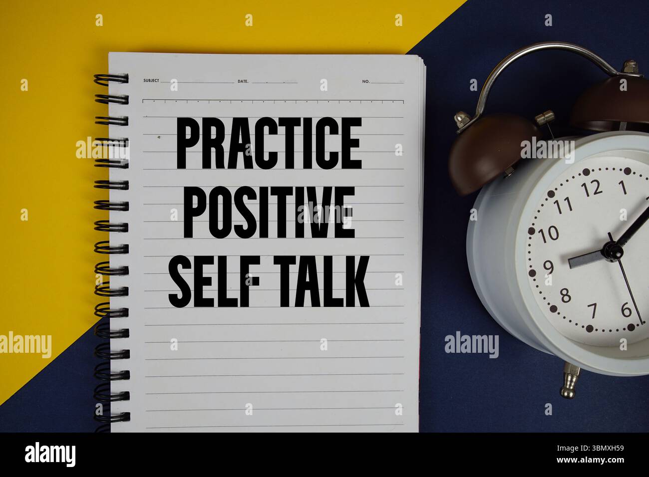 Esercitarsi con il testo di autocomunicazione positivo scritto sul blocco note con sveglia su sfondo giallo Foto Stock