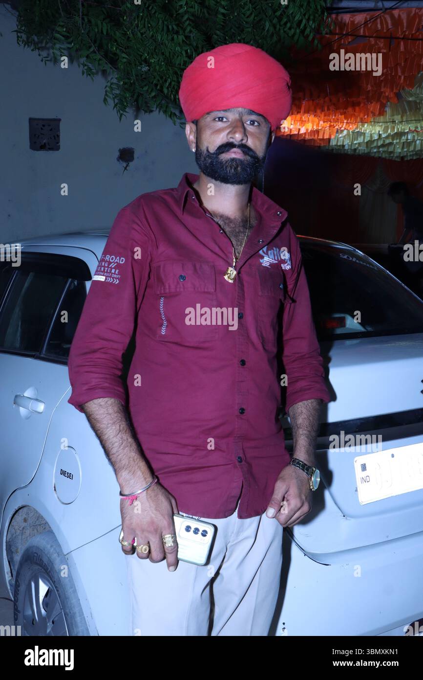 Giovane indiano che indossa un turbante tradizionale con pantaloni moderni Foto Stock