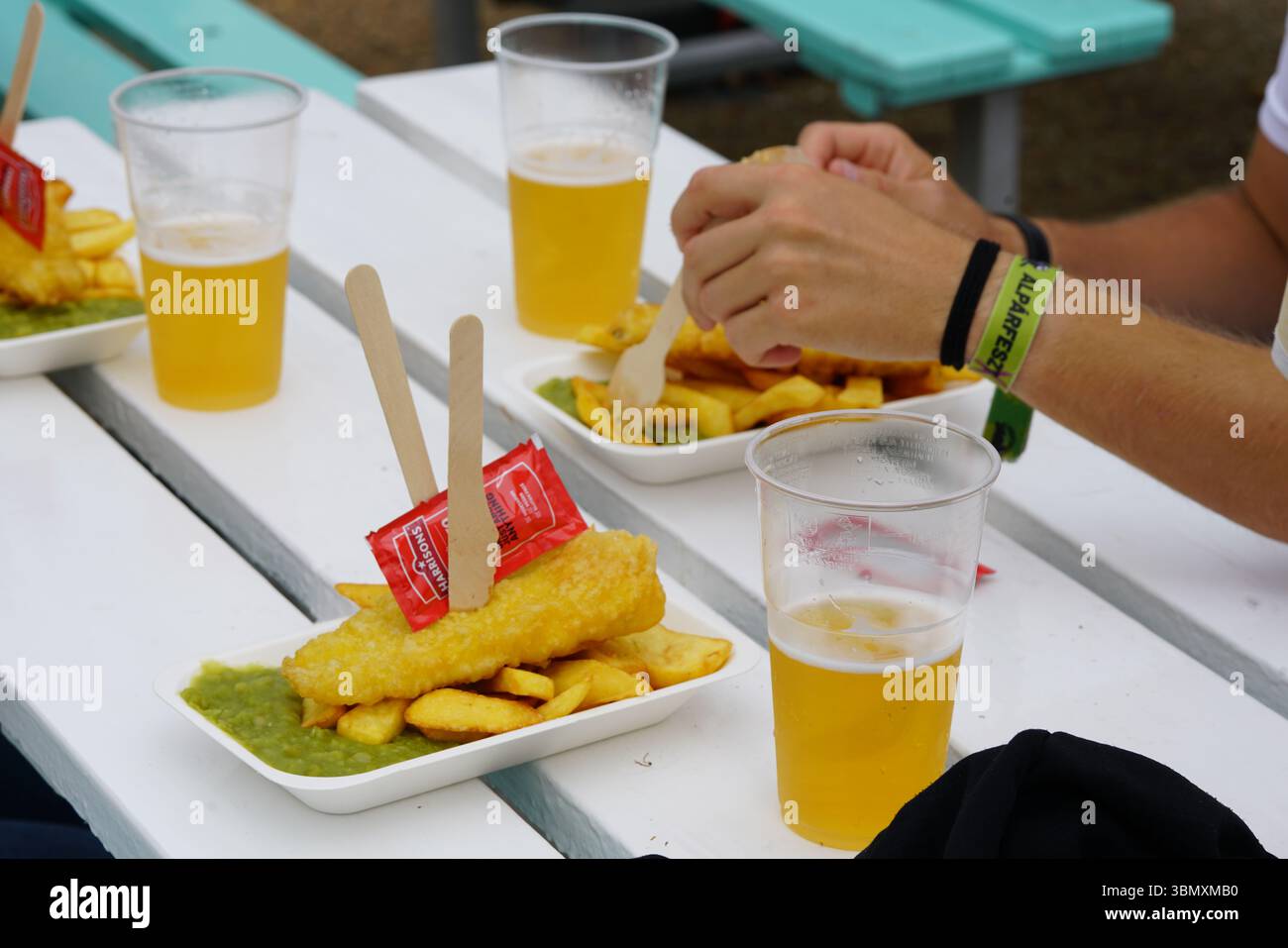 Pasto a base di pesce e patatine fritte nel patio all'aperto con bicchieri di birra fredda. Brighton, Inghilterra Foto Stock