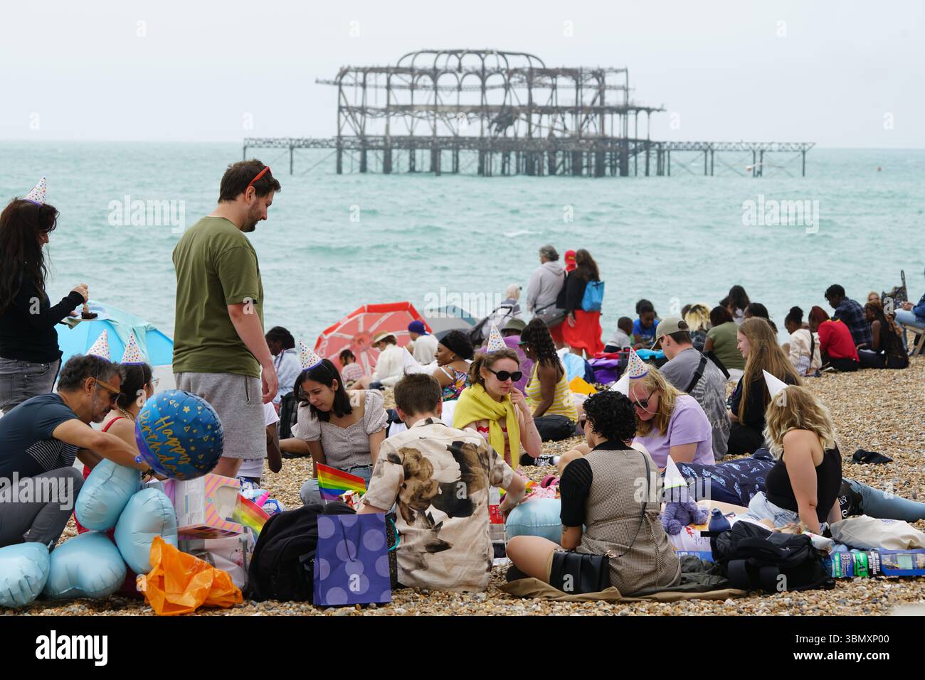 Gruppo di persone che si godono una riunione sulla spiaggia con una vista panoramica sull'oceano. Brighton, Inghilterra Foto Stock