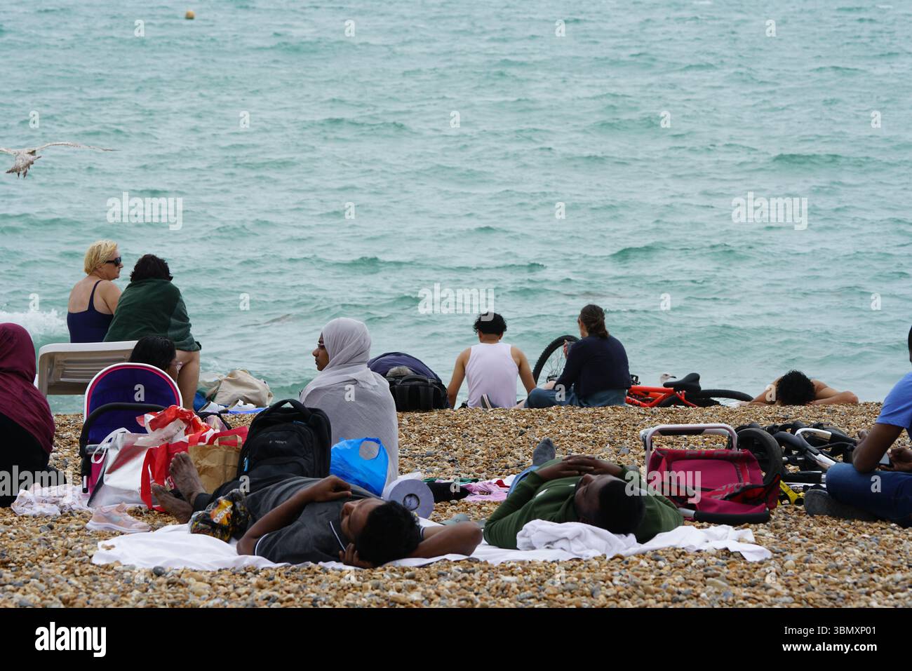 Gruppo di persone che si godono una riunione sulla spiaggia con una vista panoramica sull'oceano. Brighton, Inghilterra Foto Stock