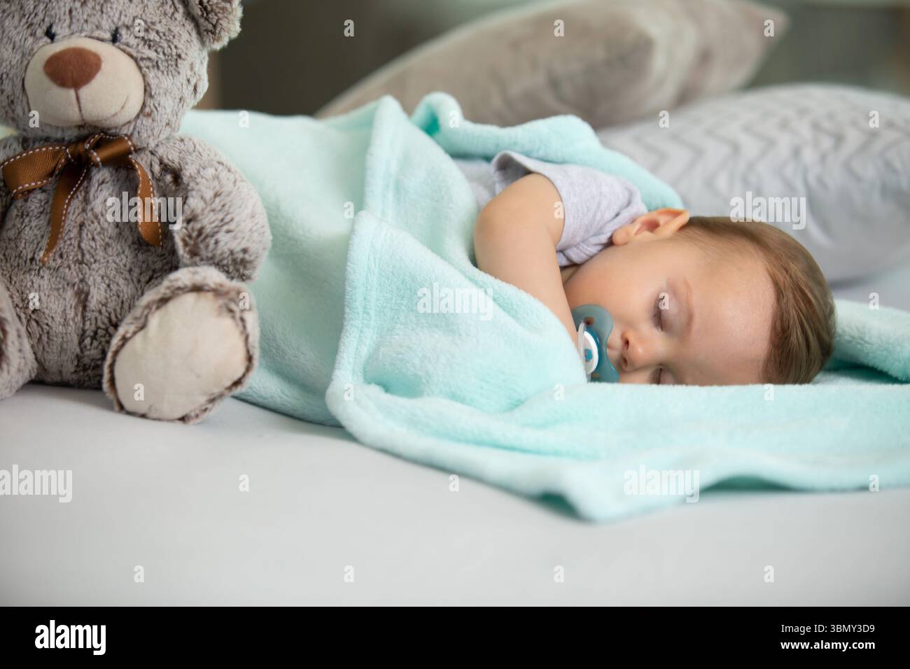 il bambino dorme con un succhietto e un orsacchiotto Foto Stock