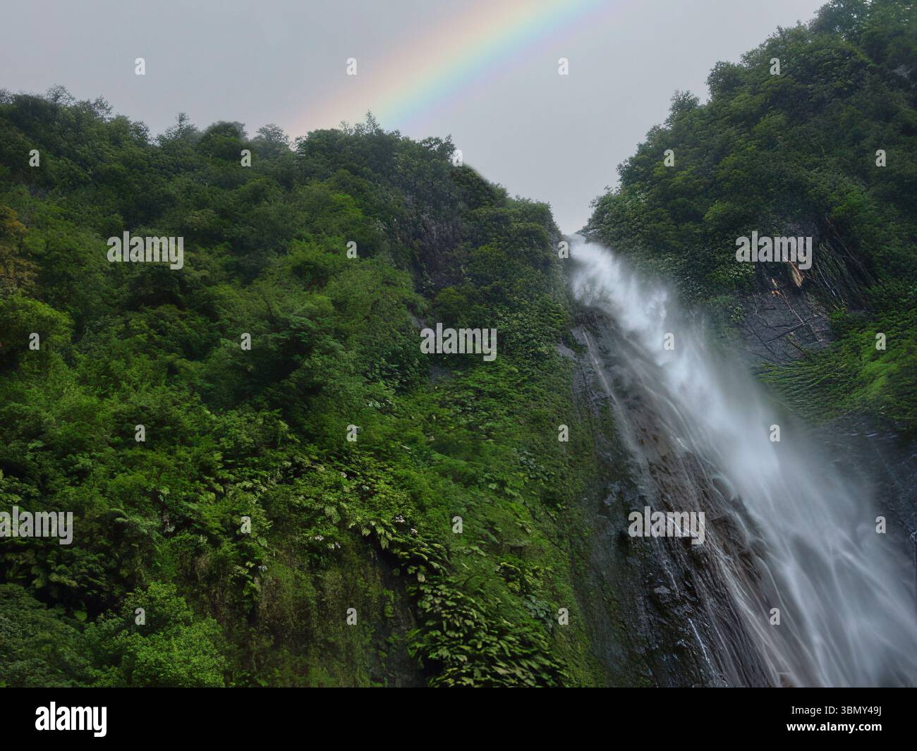 La maestosa cascata che scende lungo la lussureggiante giungla con l'arcobaleno sopra Foto Stock