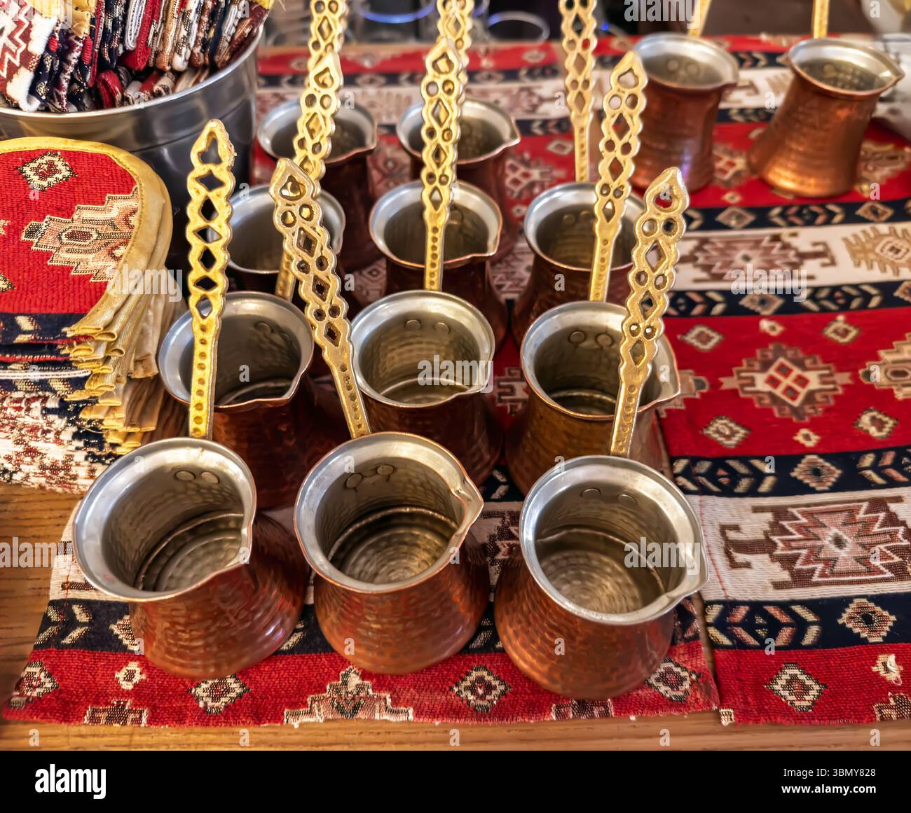 Preparazione per l'erogazione di caffè turco forte. Un gruppo di pentole in rame martellato (cezve) in stile vintage su un tradizionale fondo tessile. Attrezzatura per Foto Stock